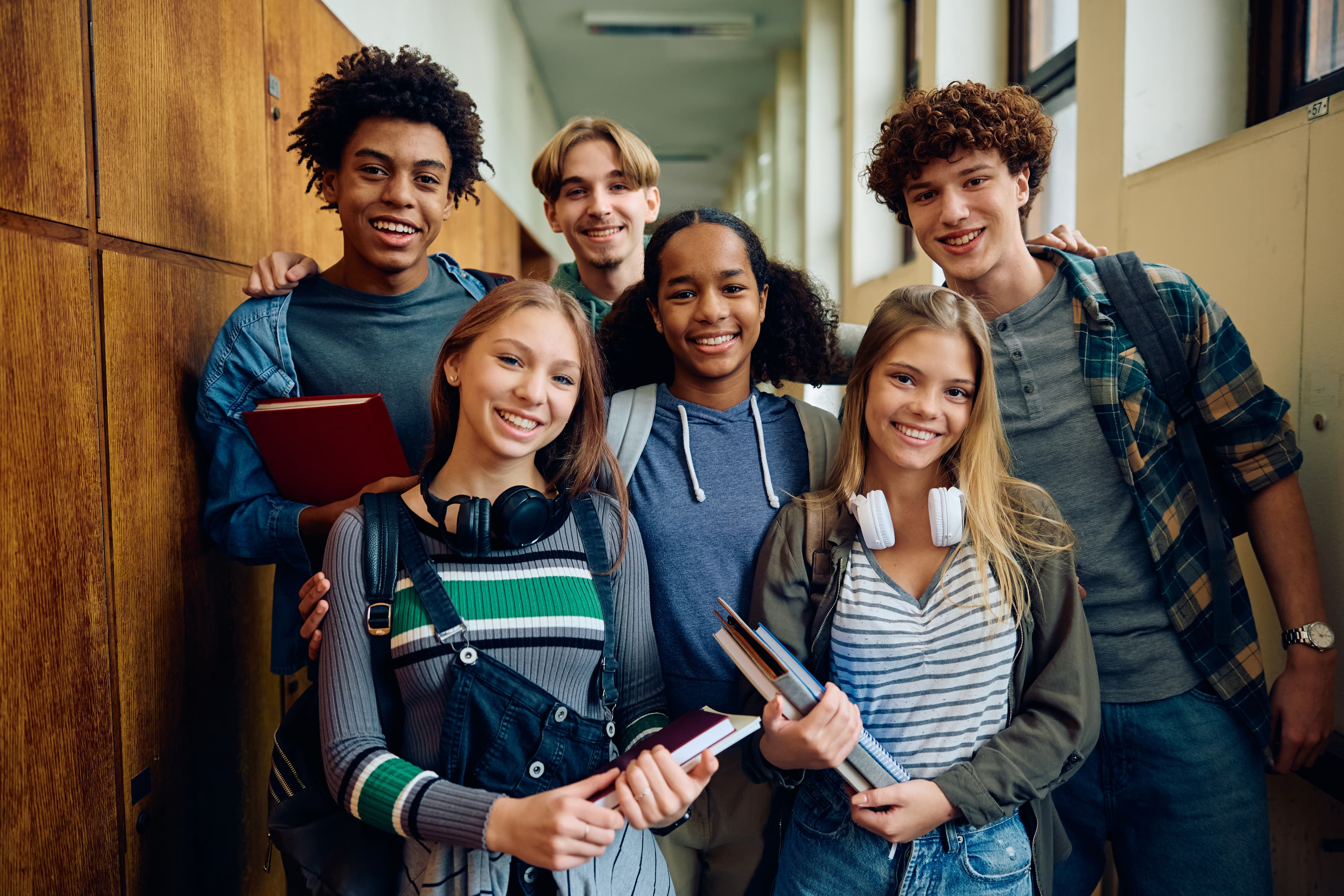 Ensino Médio: grupo de jovens estudantes sorrindo no corredor.